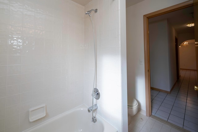 bathroom with tile patterned flooring, tiled shower / bath, and toilet