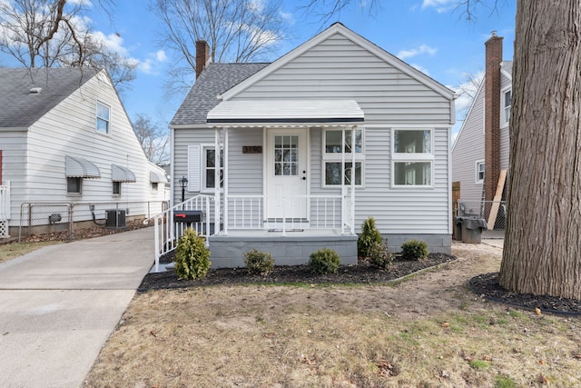 bungalow-style house with a front lawn and central AC unit