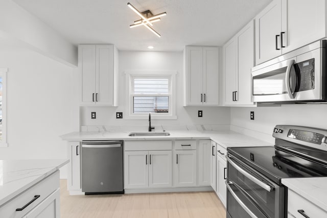 kitchen featuring light stone countertops, white cabinetry, sink, and stainless steel appliances