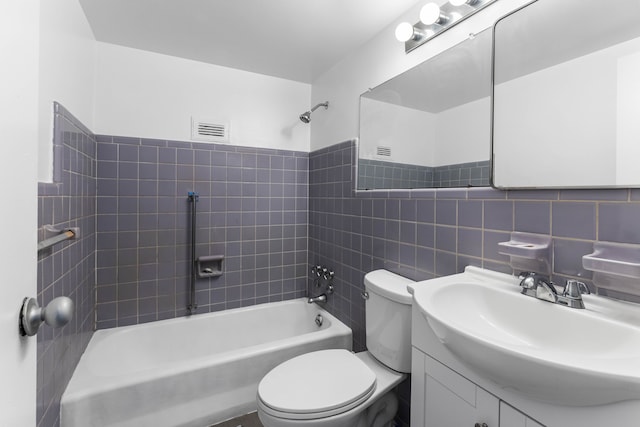 full bathroom with tile walls, tiled shower / bath combo, vanity, decorative backsplash, and toilet