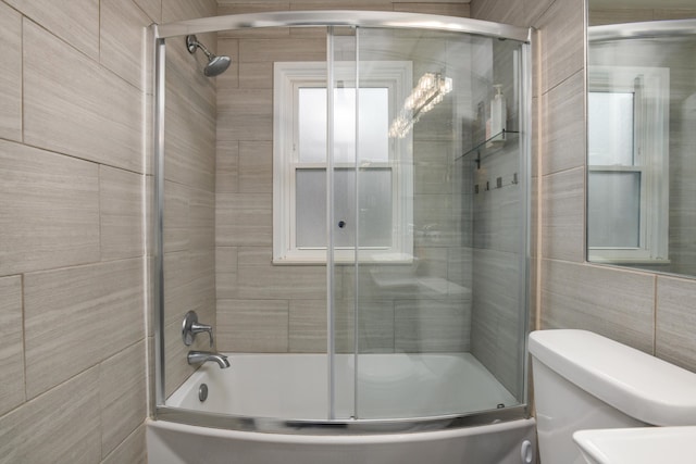 bathroom featuring enclosed tub / shower combo, tile walls, and toilet