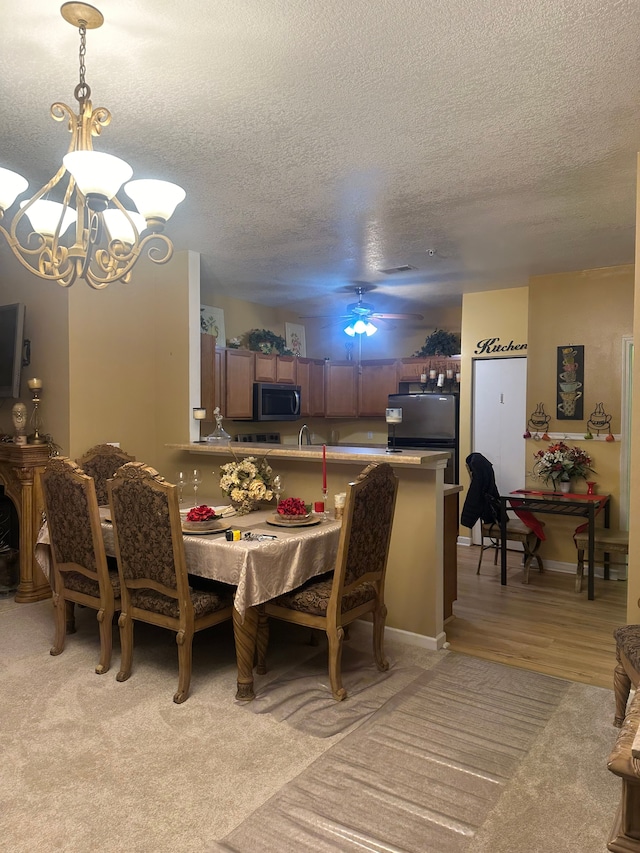 carpeted dining space with ceiling fan with notable chandelier and a textured ceiling