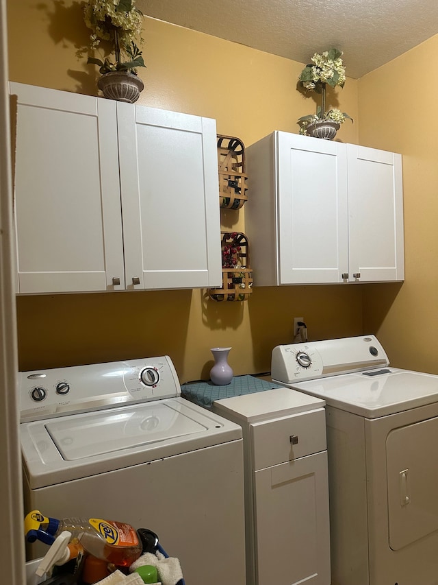 washroom featuring washer and clothes dryer, cabinets, and a textured ceiling