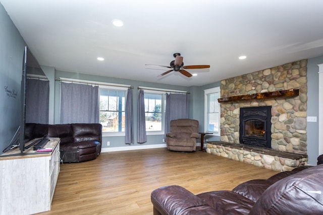 living room featuring a fireplace, ceiling fan, and light wood-type flooring