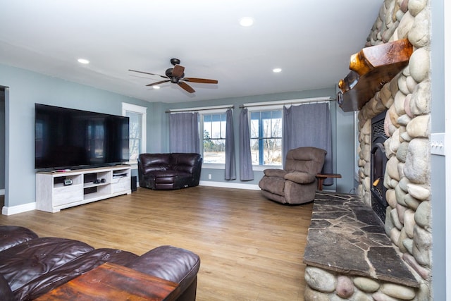 living room featuring ceiling fan, light hardwood / wood-style flooring, and a fireplace