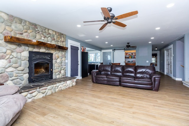 living room featuring ceiling fan, a fireplace, and light hardwood / wood-style flooring