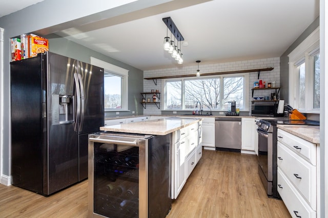 kitchen featuring white cabinetry, stainless steel appliances, wine cooler, hanging light fixtures, and a kitchen island