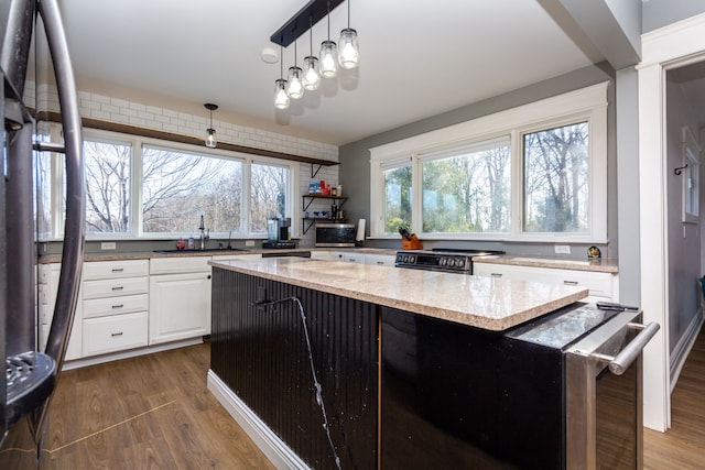 kitchen featuring a kitchen island, white cabinetry, sink, dark hardwood / wood-style floors, and light stone counters