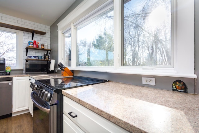 kitchen with light stone counters, white cabinetry, appliances with stainless steel finishes, and dark hardwood / wood-style floors