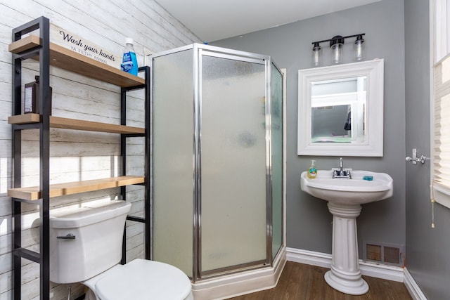 bathroom with toilet, a shower with shower door, and hardwood / wood-style flooring