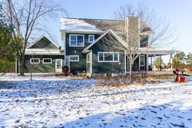 snow covered rear of property featuring a porch