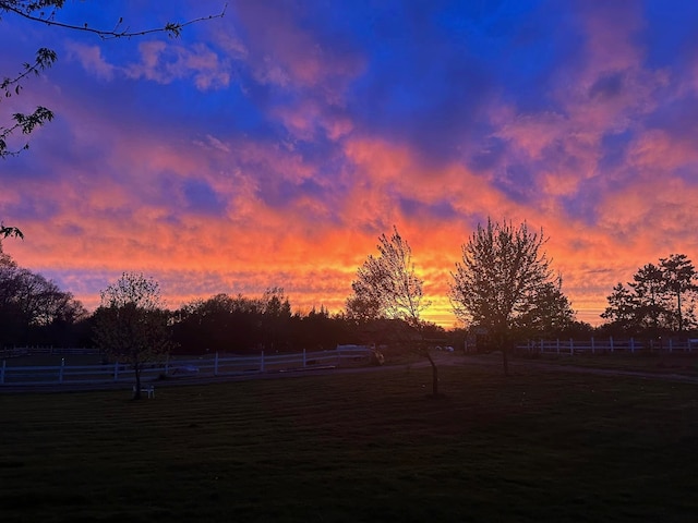 yard at dusk featuring a rural view