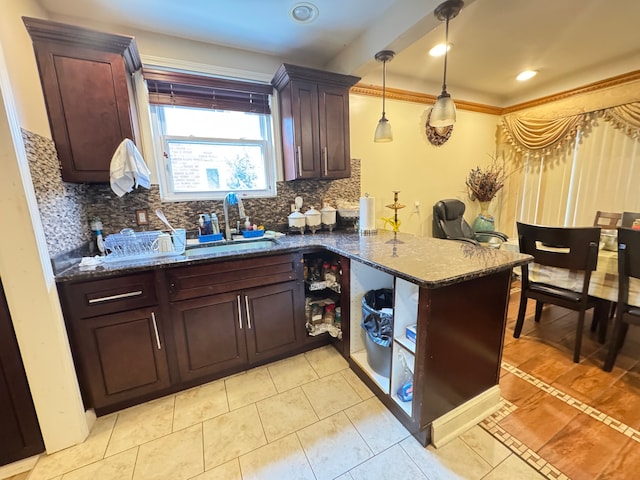 kitchen with dark stone counters, kitchen peninsula, light tile patterned floors, and hanging light fixtures