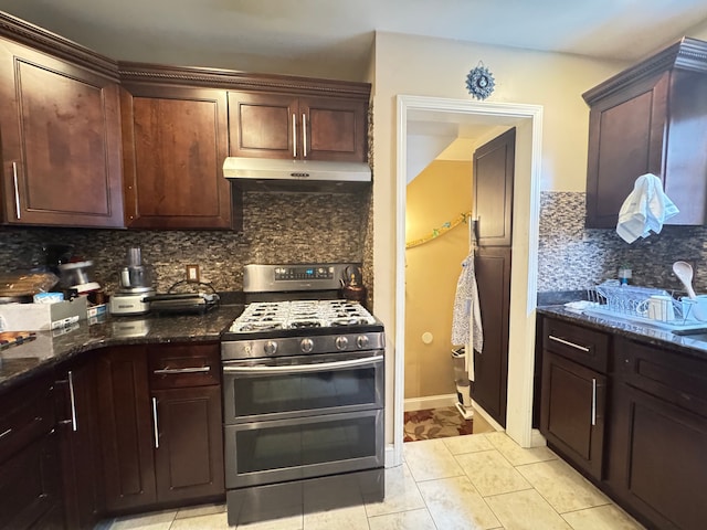 kitchen with double oven range, light tile patterned floors, backsplash, and dark stone counters