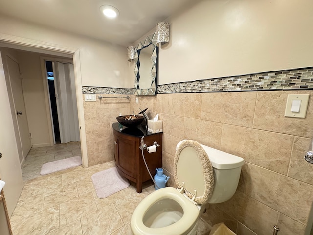 bathroom with vanity, tile walls, and toilet