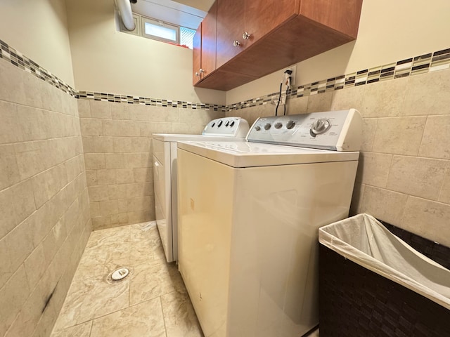 washroom featuring cabinets, light tile patterned flooring, tile walls, and washing machine and clothes dryer