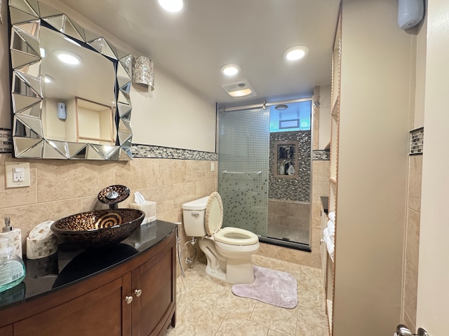 bathroom with vanity, tile walls, tile patterned flooring, toilet, and a shower with shower door