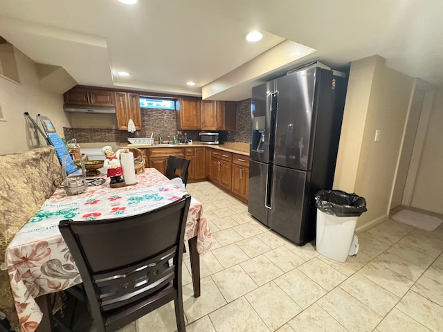 kitchen with stainless steel fridge, light tile patterned floors, and backsplash