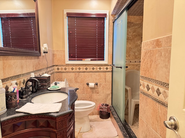 bathroom featuring toilet, vanity, tile patterned floors, and tile walls