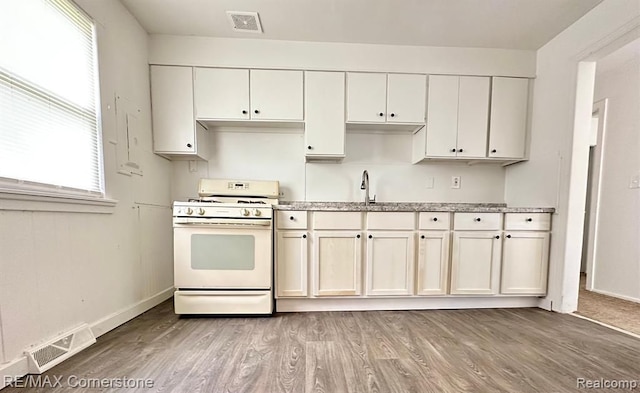 kitchen featuring white cabinetry, a wealth of natural light, gas range gas stove, and light wood-type flooring