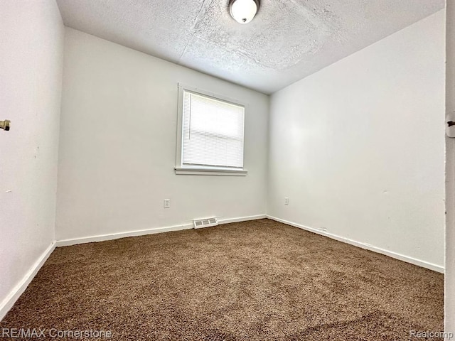 unfurnished room with carpet floors and a textured ceiling