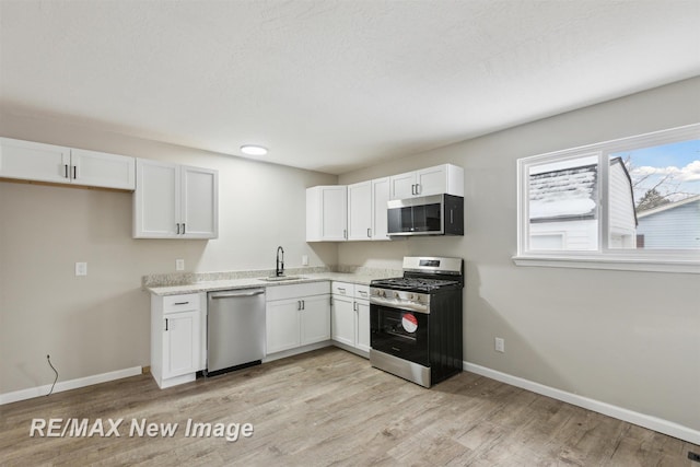 kitchen featuring white cabinets, light hardwood / wood-style floors, sink, and stainless steel appliances