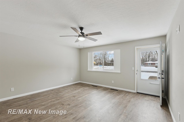 unfurnished room featuring ceiling fan, wood-type flooring, and a textured ceiling