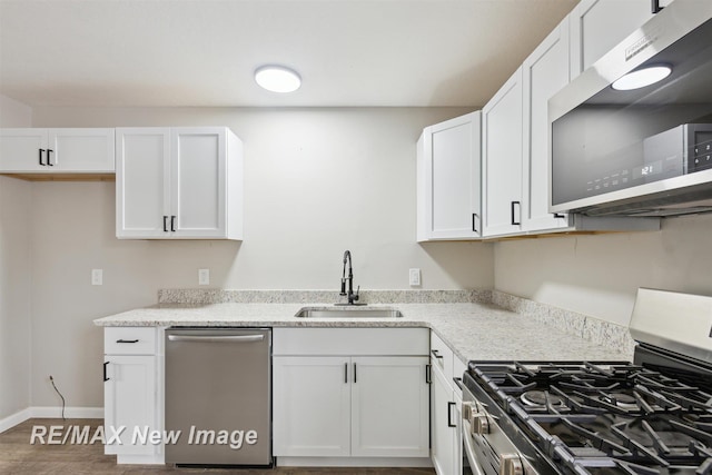 kitchen with white cabinets, stainless steel appliances, light stone countertops, and sink