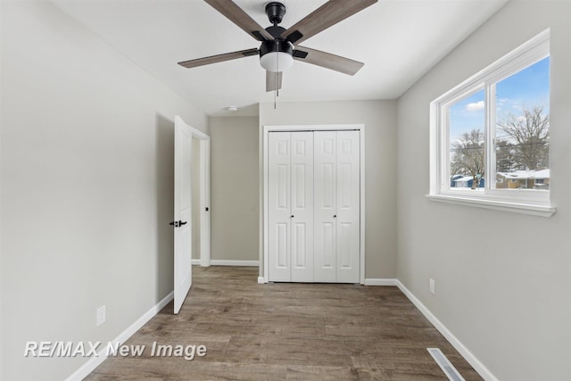 unfurnished bedroom featuring ceiling fan, wood-type flooring, and a closet