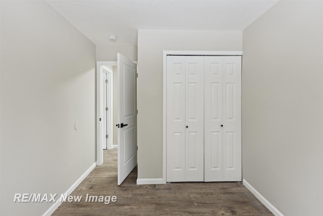 unfurnished bedroom with dark hardwood / wood-style floors and a closet