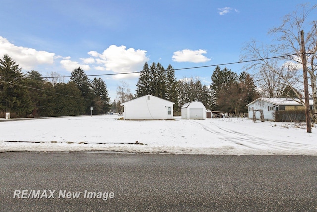 yard covered in snow with a garage and an outbuilding