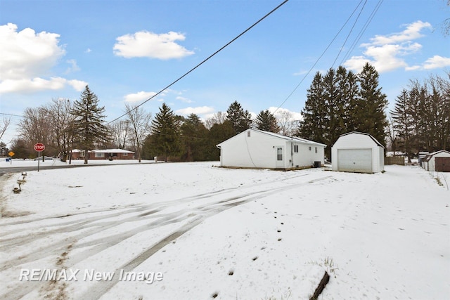 yard covered in snow featuring a garage and an outdoor structure