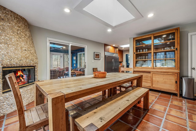 dining room with a fireplace, a skylight, and tile patterned floors