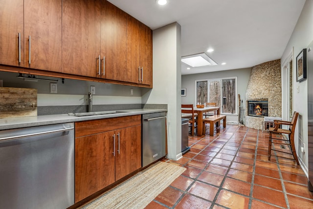 kitchen with dishwasher, a skylight, a stone fireplace, and sink