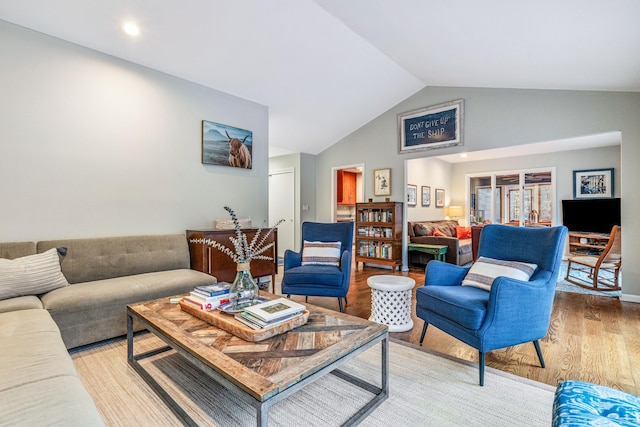 living room featuring lofted ceiling and light hardwood / wood-style flooring