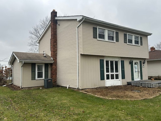 rear view of house featuring a lawn and central air condition unit