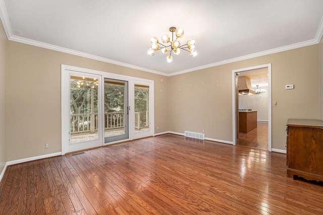 spare room with a chandelier, wood-type flooring, and ornamental molding