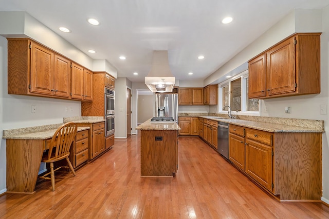 kitchen with sink, a kitchen island, light stone countertops, light hardwood / wood-style floors, and stainless steel appliances