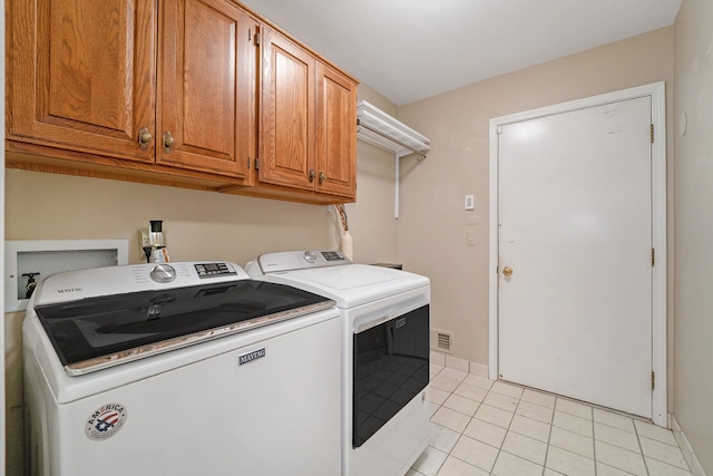 clothes washing area featuring cabinets, light tile patterned floors, and washer and dryer