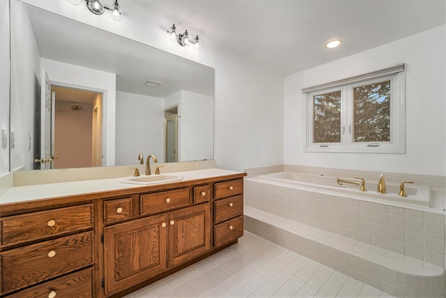 bathroom featuring tile patterned floors, tiled tub, and vanity