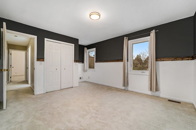 unfurnished bedroom featuring light carpet and a closet