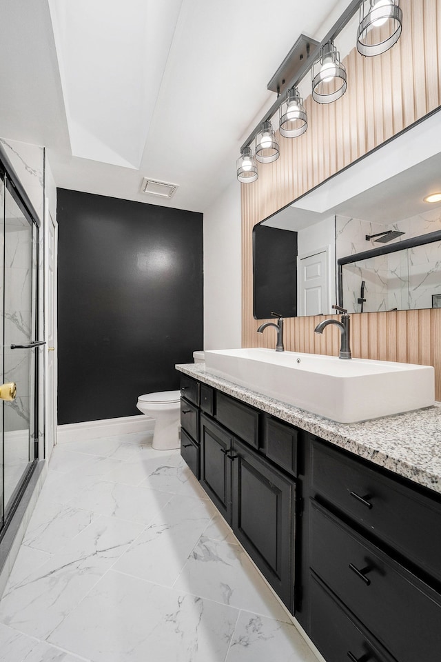 bathroom featuring vanity, toilet, and a shower with shower door