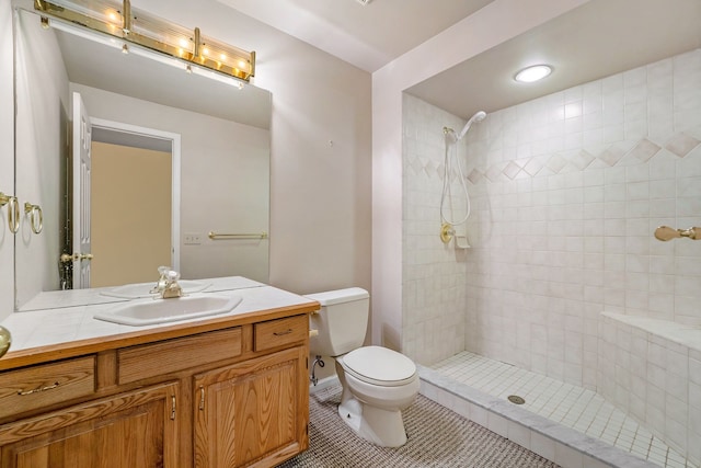 bathroom featuring tile patterned floors, vanity, toilet, and a tile shower