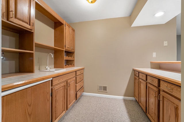 interior space featuring tile countertops, light colored carpet, and sink