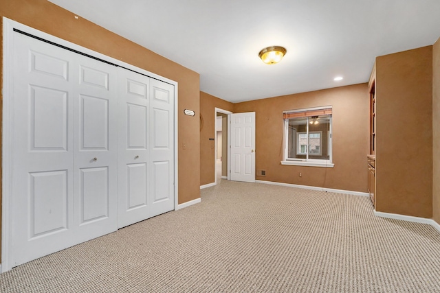 unfurnished bedroom featuring light carpet and a closet