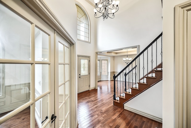 foyer with crown molding, dark hardwood / wood-style flooring, a chandelier, and french doors