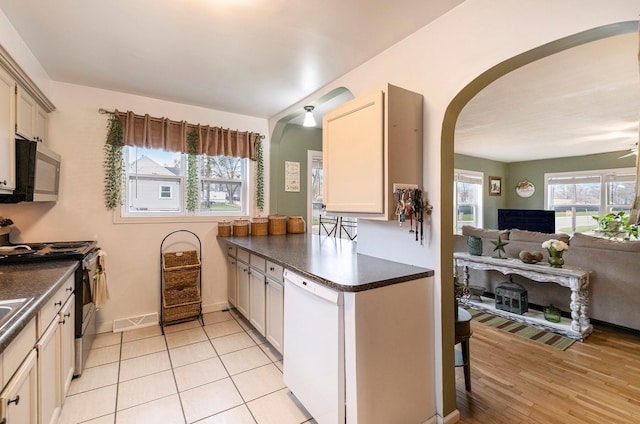 kitchen featuring light tile patterned flooring, kitchen peninsula, stainless steel appliances, and cream cabinets