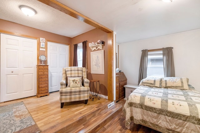 bedroom featuring wood-type flooring, a textured ceiling, and multiple windows