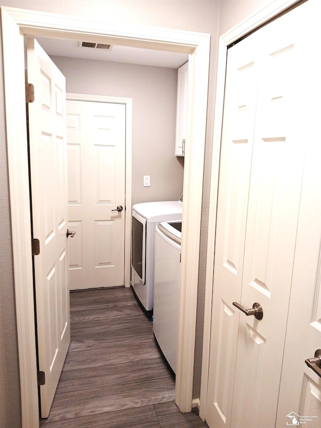 washroom featuring cabinets, dark wood-type flooring, and washing machine and clothes dryer