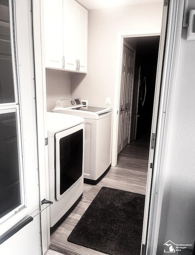 laundry room with washer and clothes dryer, cabinets, and light wood-type flooring